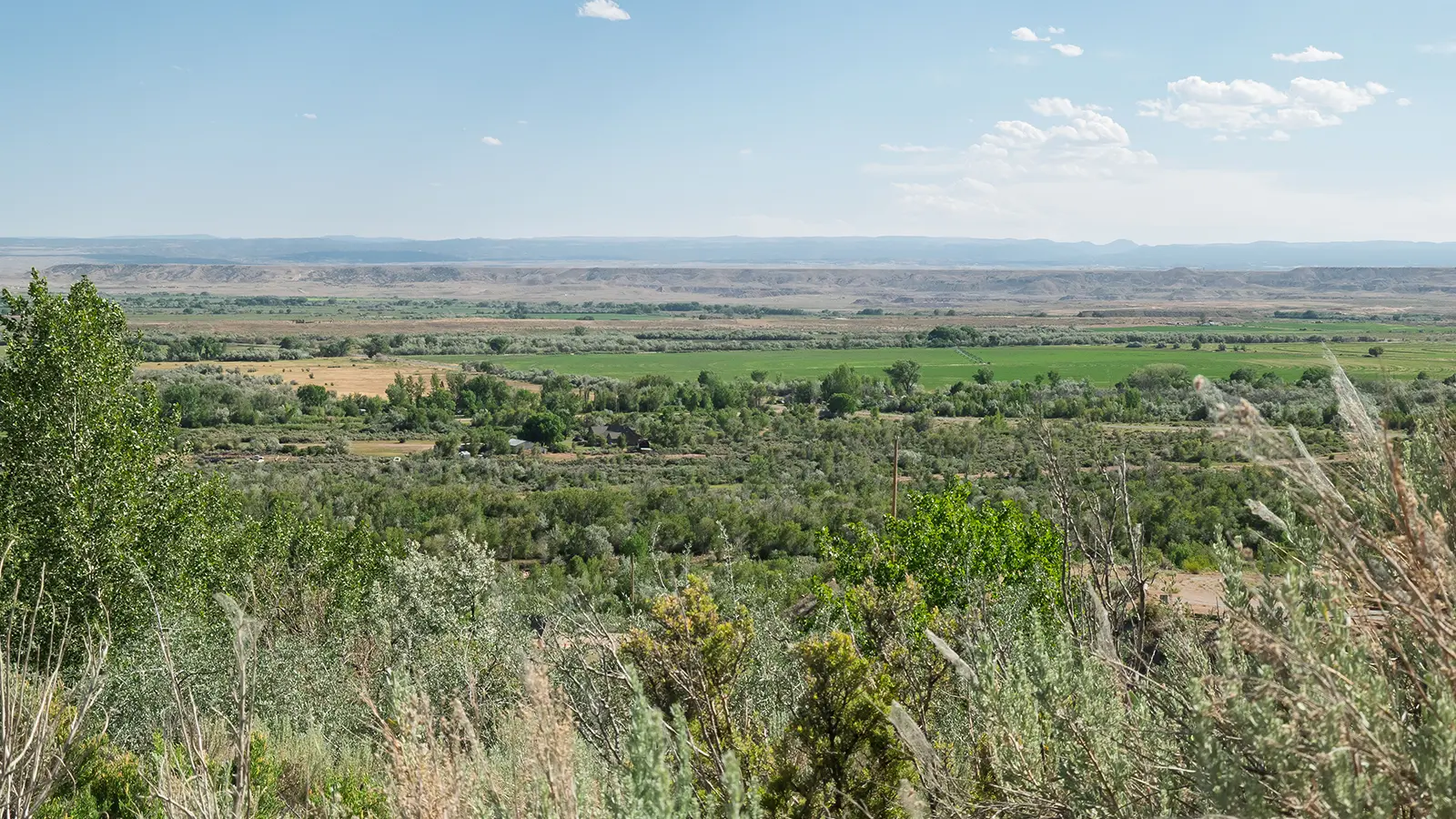A green, irrigated valley interspersed by arid brushland and rugged badlands.