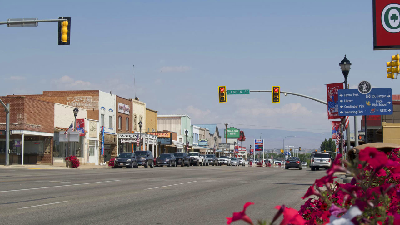 Roosevelt main street with cars parked at a stop light, storefronts and planter boxes alongs the sidewalks
