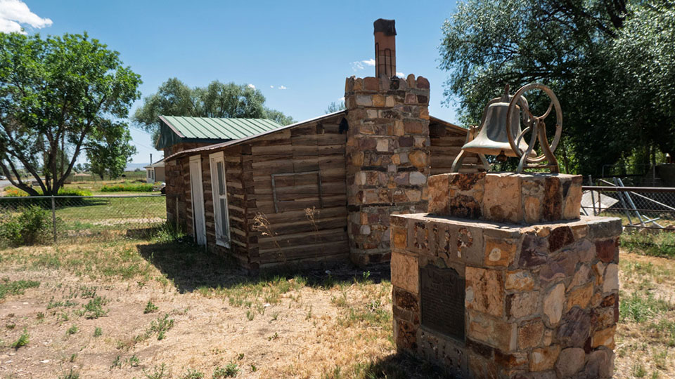 An small cabin and historical monument featuring an old bell
